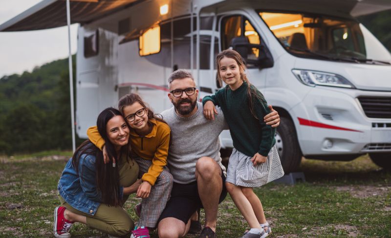 happy-family-looking-at-camera-outdoors-at-dusk-c-2022-01-18-23-33-51-utc Familia con caravana